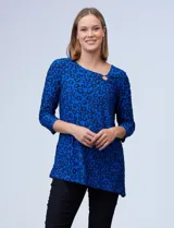 Blusa azul con estampado de círculos negros, de tejido texturado con escote en V descentrado y aplique de aro metálico.