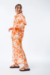 Camisa naranja con estampado floral blanco, de corte holgado, manga larga y cuello camisero.
