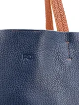 Cartera tipo tote bag de cuero, con diseño bicolor en azul marino y tostado, asas largas para el hombro y costuras reforzadas.