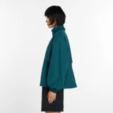 Campera deportiva New Balance de la colección Trackside, color verde oscuro. Presenta cuello alto, cierre frontal completo, mangas largas con puños elásticos y logo de la marca bordado en el pecho. Confeccionada en material ripstop resistente al viento y al agua, con diseño de ventilación.