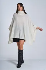 Poncho tejido color beige, con cuello alto y corte asimétrico.