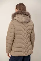 Campera corta capitoneada con diseño de costuras en zigzag, cierre frontal y capucha desmontable con borde de piel sintética. Cuenta con bolsillos laterales con cierre.