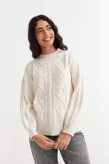 Sweater de punto color crema con diseño de ochos y rombos en el frente y mangas. Presenta cuello redondo, puños y ruedo acanalados, con un calce holgado.