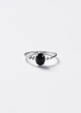 Anillo de plata 925 con una zirconia negra central de corte ovalado y pequeñas piedras brillantes en los laterales.