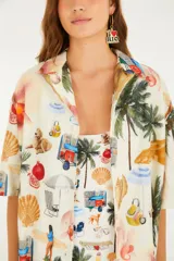 Camisa de lino y algodón color crudo con estampado de escenas de playa tropicales, de corte holgado, con cuello abierto y mangas cortas.