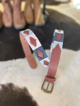 Cinturón de cuero en tono tostado con bordado a mano de hilos encerados en tonos marrones y beige con motivos geométricos, y hebilla metálica rectangular.