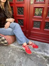 Championes de cuero color rojo con detalles en blanco, diseño de perfil bajo, suela flexible y cierre con cordones.