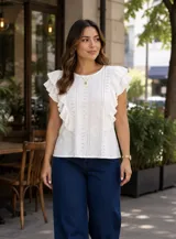 Blusa de broderie color amarillo, sin mangas, con diseño de volados en los hombros y detalles perforados en el tejido.