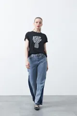 Remera blanca de manga corta con estampado frontal de un florero rojo con rayas verticales y un ramo de flores azules y rojas.