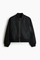 Campera bomber de nylon color negro, con cuello, puños y bajo acanalados. Presenta cierre frontal, bolsillos laterales con botón a presión y un bolsillo con cierre en la manga.