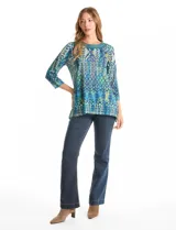 Blusa de calce relajado con estampado geométrico multicolor en tonos azules, verdes y amarillos. Presenta escote redondo con detalle tejido en el contorno, mangas tres cuartos y silueta levemente evasé.