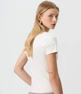 Remera de algodón con elastano color blanco, de corte ajustado, manga corta y cuello redondo. Presenta un detalle frontal de botones dispuestos en forma de estrella.