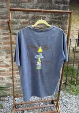 Remera de algodón premium con efecto lavado, manga corta y cuello redondo. Presenta un estampado gráfico en la espalda con personajes coloridos y la frase Good Trips, Good Friends.