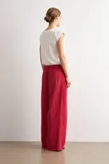 Pantalón de corte recto y pinzas delanteras, color rojo, con bolsillos laterales y cierre frontal con botón y cremallera.