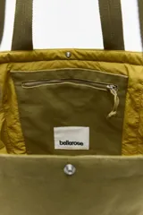 Bolso tote reversible color verde militar confeccionado en lona, con doble asa superior y logo estampado vertical en el frente.