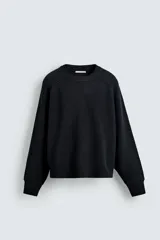 Jersey de punto con diseño boxy fit, cuello redondo y manga larga. Presenta una textura acanalada y acabados en rib en cuello, puños y ruedo.