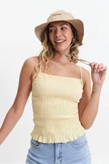 Musculosa de tiras finas color amarillo pálido, con textura elastizada y volados en el ruedo.