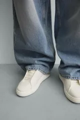 Zapatilla negra de cordones, con parte superior lisa y cordonera oculta. Posee suela con volumen a tono.