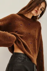Sweater de punto color marrón con diseño de pequeños corazones bordados en color violeta, de corte holgado y manga larga.
