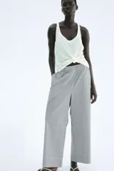 Pantalón tobillero de algodón a rayas verticales blancas y azul marino, con cintura elástica fruncida y corte ancho en las piernas.