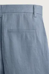 Bermuda relaxed fit confeccionada en lino color celeste, con bolsillos laterales, bolsillos traseros de vivo y cierre frontal con cremallera y botón.