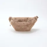 Riñonera de diseño compacto confeccionada en piel sintética de pelo largo color gris topo. Cuenta con un compartimento principal con cierre metálico y tiradores de cordón.