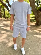 Conjunto deportivo gris melange compuesto por remera de manga corta y short con cordón ajustable en la cintura.
