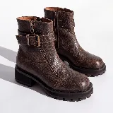 Bota corta de cuero vacuno negro con textura granulada, diseño de punta cuadrada y suela de goma tipo track con plataforma. Presenta un cierre frontal decorativo, una tira con hebilla metálica en la parte superior de la caña y un cierre lateral interno.