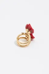 Anillo en espiral de metal dorado con diseño de dos rosas rojas de resina y detalles de cristales negros en el centro.