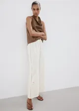 Pantalón palazzo color blanco con detalles bordados en el bajo de las piernas, tiro medio y cintura elástica con cordón ajustable.