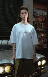 Remera blanca de corte oversize con cuello redondo y manga corta. Presenta un estampado minimalista en el pecho con la frase "Au revoir, shoshanna!" en tipografía negra.