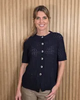 Cardigan de punto color tostado, de manga corta y cuello redondo, con cierre frontal de botones y diseño texturizado.