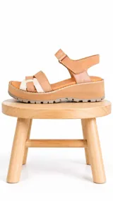 Sandalia de plataforma liviana con suela track, confeccionada en 100% cuero en tonos camel y marfil, con tiras entrelazadas en la parte delantera y tira ajustable con velcro en el talón.