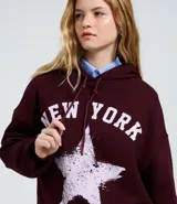 Buzo con capucha y cordones ajustables, de corte holgado y manga larga. Presenta un diseño estampado en el frente con la frase 'New York' y una estrella con efecto desgastado.
