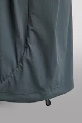 Chaqueta técnica de corte relajado, confeccionada en tejido compacto y elástico. Presenta cuello y puños acabados en rib, cierre frontal con cremallera, bolsillos frontales con cremallera oculta y bajo ajustable con elástico en los laterales.