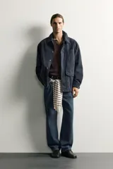 Sobrecamisa regular fit confeccionada en tejido de algodón negro con estructura canvas. Tiene cuello solapa, manga larga con puño abotonado, bolsillos de plastrón con solapa en la cadera y un bolsillo en el pecho. Cierre frontal con botones ocultos bajo solapa.