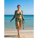 Conjunto de traje de baño de tres piezas con estampado de hojas tropicales en tonos blanco y negro. Incluye un top tipo tankini con cordón ajustable en el centro, un short de tiro alto y una camisa abierta de manga larga tipo salida de baño.