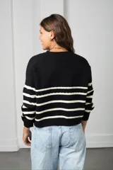 Saco de punto con cierre frontal, diseño a rayas horizontales negras sobre base color crema, de manga larga y calce holgado.