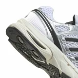 Championes Adidas Adistar Control 5 de malla blanca con superposiciones de cuero sintético metalizado plateado y detalles en negro. Cuentan con las icónicas tres tiras de Adidas en los laterales y una suela robusta con amortiguación.