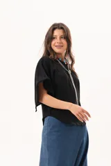 Blusa de silueta relajada y caída fluida, color negro, con escote redondo y mangas amplias.