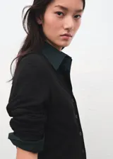 Cardigan de punto fino color negro, con cuello en V, manga larga y cierre frontal de botones.