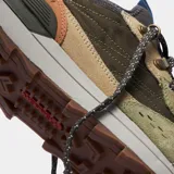 Championes Merrell modelo Alpine 83, con diseño inspirado en el senderismo retro. Presentan una combinación de gamuza y tela en tonos verde oliva, beige y marrón, con suela de goma y cordones técnicos.