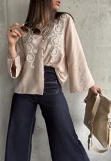 Camisa beige de manga larga con bordado floral blanco en el frente y cuello mao.