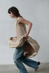 Vestido midi sin mangas de cuello redondo, con falda amplia con frunces y bolsillos laterales ocultos. Presenta cierre en la espalda con abertura y botón.