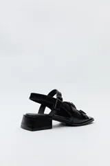 Sandalia negra de cuero sintético con textura símil reptil, taco medio cuadrado y múltiples tiras con hebillas metálicas ajustables.