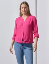 Blusa color fucsia de gasa, marca Zac & Rachel. Cuello a la base, escote en V y abertura central con botones. Delantera con bolsillo aplicado. Largo de manga regulable con presilla y botón. Terminación opcional de nudo en ruedo.