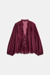 Blusa de escote en pico con volantes decorativos, manga larga con puños elásticos y cierre frontal con botones.
