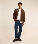 Campera masculina de estilo casual con cuello inglés, cierre frontal por cremallera, bolsillos laterales y ajuste elástico en el bajo. Presenta detalles de recortes en la parte superior delantera.