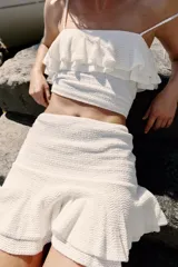 Minifalda blanca de punto con cintura elástica y diseño con volantes en el bajo.