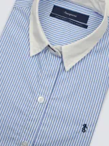 Camisa blanca de algodón, de corte suelto, manga larga y cuello clásico, con cierre frontal de botones y bordado sutil en el pecho.